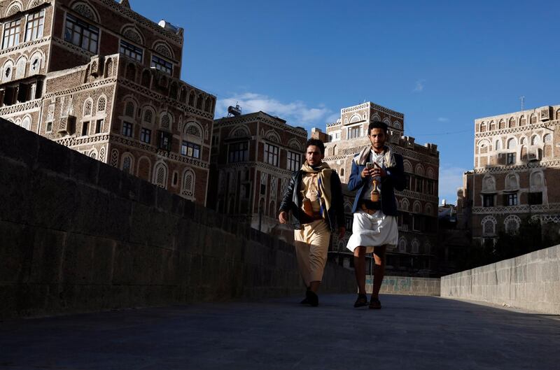 Yemenis walk past historic buildings in the old quarter of Sanaa. EPA