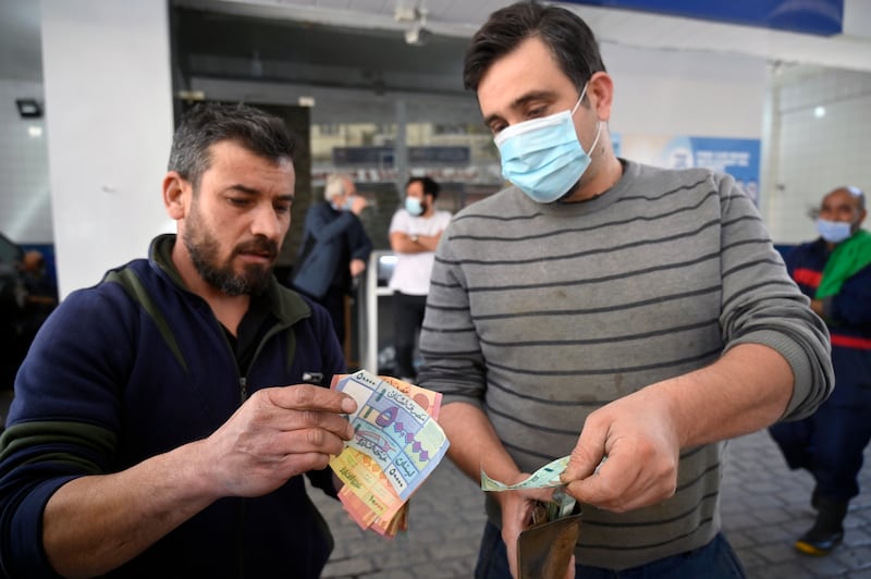 An attendant counts Lebanese pounds next to a customer at a gas station in Beirut.