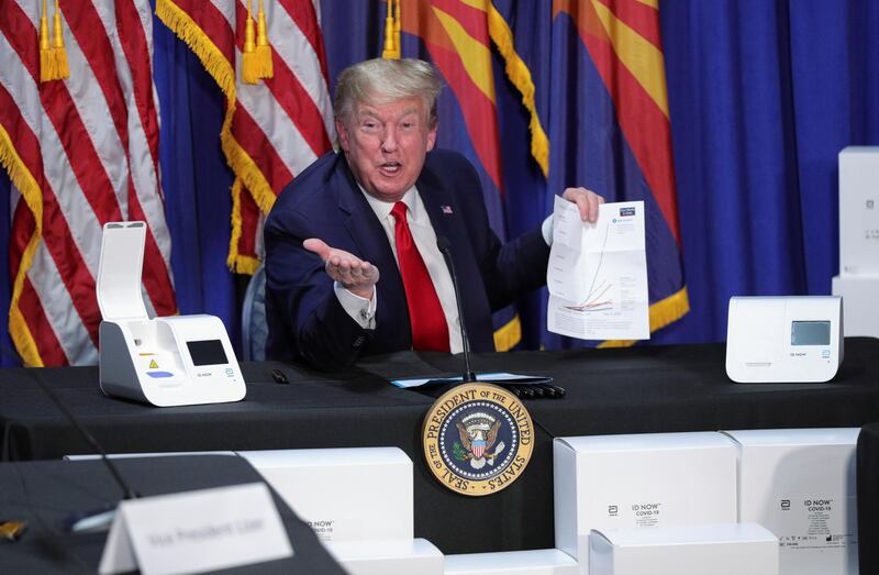 President Donald Trump holds up a chart on global coronavirus disease  testing as he sits in front of coronavirus testing machines and their boxes that he brought with him from Washington for his visit to a Honeywell manufacturing plant in Phoenix, Arizona. Reuters