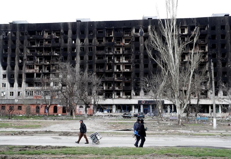 Local residents walk past a burned building during Ukraine-Russia conflict in the southern port city of Mariupol last week. Reuters