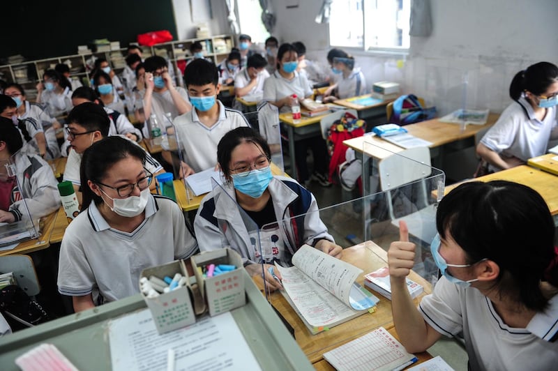 Students chat behind a plastic partition in a classroom at a high school in Wuhan in China's central Hubei province. AFP