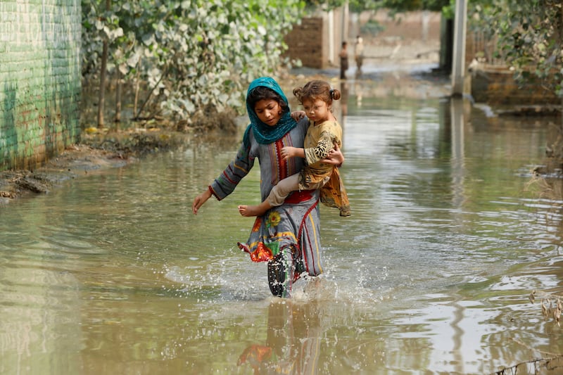 A girl carries her sibling as she walks through floodwaters in Nowshera, Khyber Pakhtunkhwa. Reuters