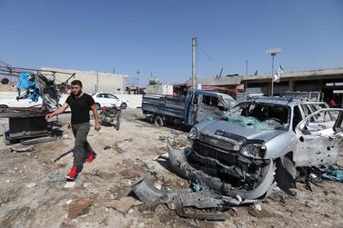 A Syrian walks past damaged cars following a reported air strike on a market in the town of Saraqeb in the northwestern province of Idlib. AFP 