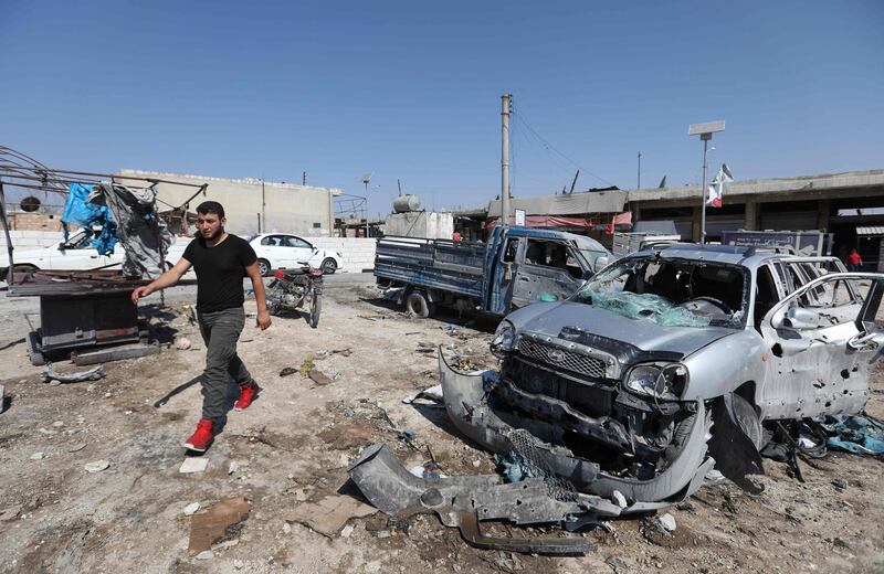 A Syrian walks past damaged cars following a reported air strike on a market in the town of Saraqeb in the northwestern province of Idlib on July 26, 2019.  / AFP / Omar HAJ KADOUR
