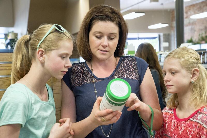 Caucasian mother and daughters reading label in nutrition store