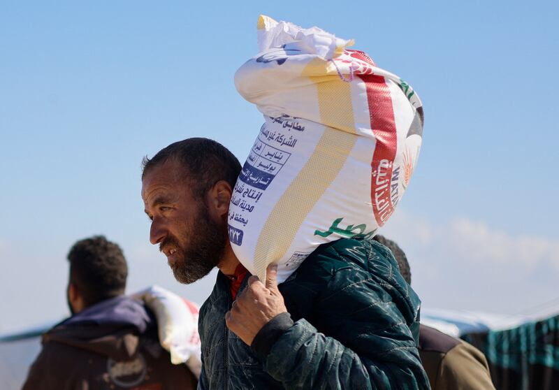 A Palestinian man carries a bag of flour, as displaced Palestinians, who fled their houses due to Israeli strikes, take shelter near the border with Egypt in Rafah. Reuters
