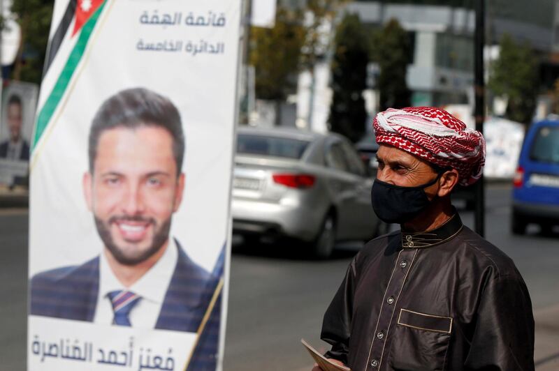 A man wearing a face mask walks past a poster of one of the candidates, ahead of parliamentary elections which will be held on November 10, amid fears over rising number of the coronavirus disease cases, in Amman, Jordan. Reuters