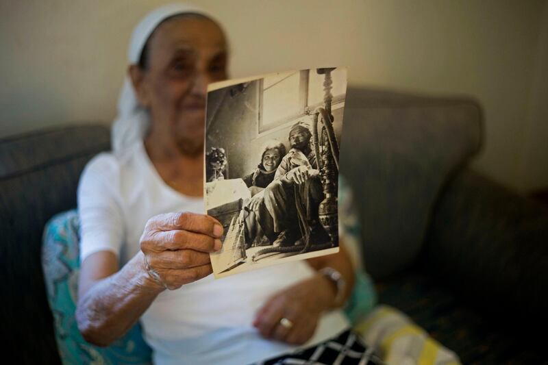 FILE - In this July 11, 2016 file photo, Yemen born Jewish Israeli Yona Josef holds a photograph dated back to the 1940's of her and her father back in Yemen in her home in Raanana, Israel. Josef said she was asked to take her 4-year-old sister Saada to a health clinic and leave her there. When she returned several hours later, she was told her sister was dead and the family was given no further details or a body to bury. The Israeli government has approved a plan to offer $50 million in compensation to the families of hundreds of Yemenite children who disappeared in the early years of the countryâ€™s establishment. But the announcement on Monday, Feb. 22, 2021, received a cool reception from advocacy groups that said the government had failed to apologize or accept responsibility for the affair. (AP Photo/Ariel Schalit, File)