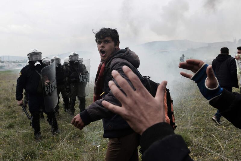 TOPSHOT - Migrants shout slogans during clashes with Greek riot police outside of a refugee camp in Diavata, a west suburb of Thessaloniki, where migrants gather on April 6, 2019. For third day hundreds of migrants gathered outside the Diavata camp near Thessaloniki after anonymous social media posts over recent days claimed that human rights groups stood ready to assist migrants in crossing into North Macedonia and on to other EU states. / AFP / Sakis MITROLIDIS

