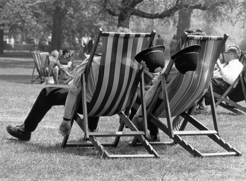 Two London policemen take the weight off their feet during a May heatwave in 1976.