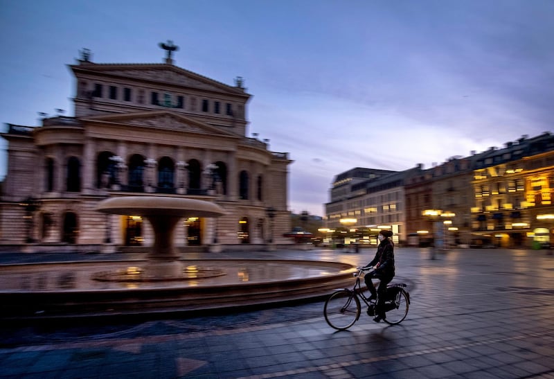 A woman wearing a face mask rides her bike past the Old Opera in Frankfurt, Germany. AP Photo