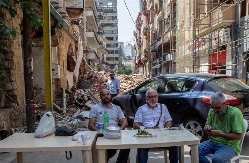 Lebanese citizens take breakfast next to an older building with damages from the Beirut port explosion, at the Gemayzeh street in Beirut, Lebanon.  EPA