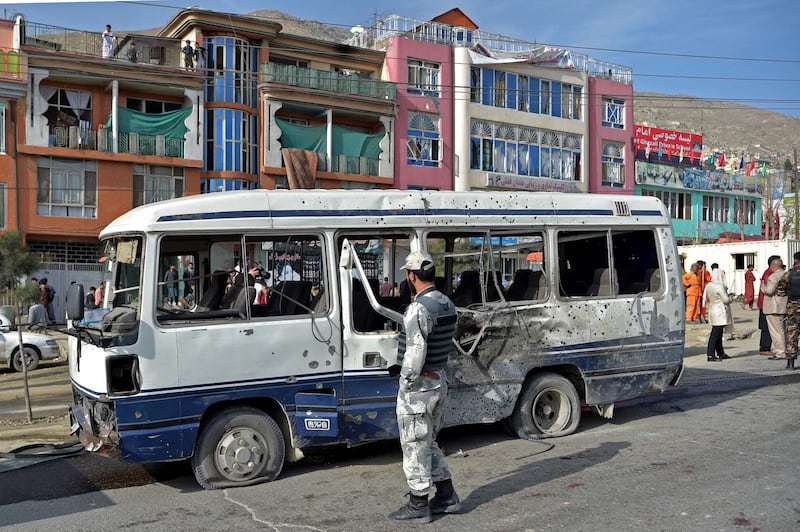 A security worker is seen near a damaged vehicle after a blast in Kabul on March 18, 2021. Wakil Kohsar / AFP