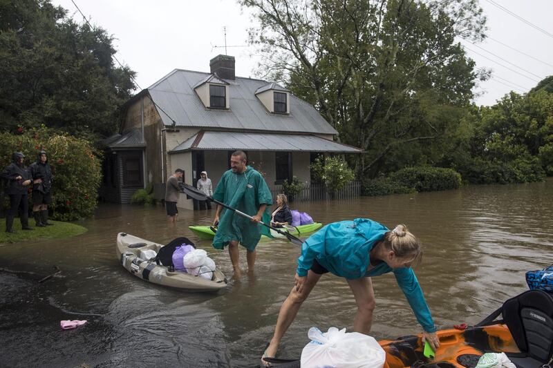 Residents unload household items from kayaks at a street submerged in floodwaters in Windsor, New South Wales, Australia. Bloomberg