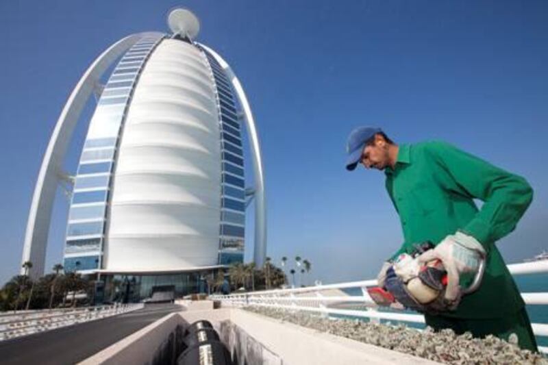 UAE - Dubai - Dec 23 - 2010: A worker cuts the grass at the Burj Al Arab Hotel. ( Jaime Puebla - The National Newspaper )