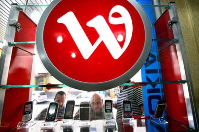 Palestinian men look at mobile phones displayed under the logo of the Al-Wataniya Palestine phone company at a shop in the West Bank city of Jenin after Israel permitted it to operate on October 14, 2009. UN special rapporteur Richard Falk, an expert on the Palestinian territories, has alleged that the ownership by Palestinian president Mahmud Abbas's two sons in the phone company was behind their father's decision to agree to put off the UN vote on the Gaza War report. The deferral sparked speculation that Israel was about to refuse to release badly-needed frequencies to run al-Wataniya Palestine unless the UN vote was postponed. AFP PHOTO/SAIF DAHLAH