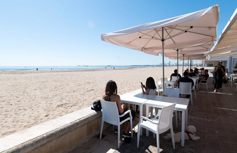 People enjoy the sunny weather at a terrace in La Malvarrosa beach in Valencia, on May 19, 2020, as some Spanish provinces are allowed to ease lockdown restrictions amid the coronavirus (COVID-19) outbreak. Spain began last week a three-phase plan to end lockdowns for half the country by the end of June. / AFP / JOSE JORDAN
