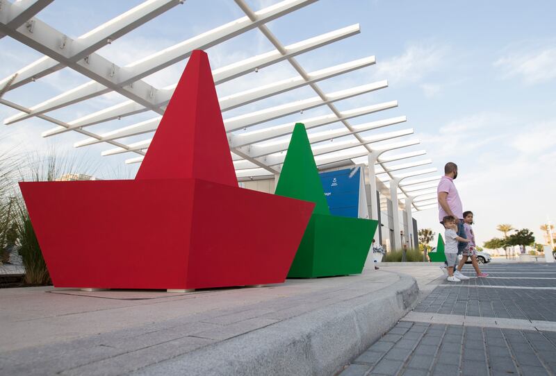 Visitors pose in front of the origami-style boats.