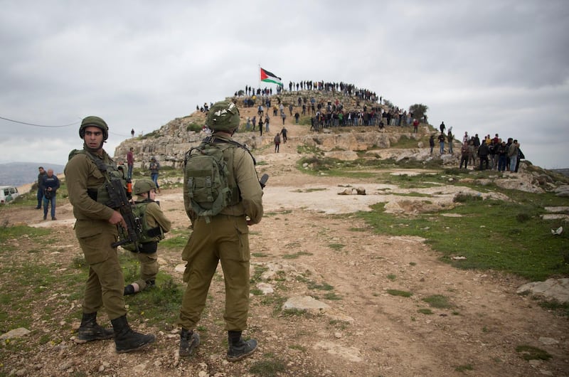 FILE - In this Monday, March 2, 2020 file photo, Israeli soldiers take position as Palestinian demonstrators gather during a protest against expansion of Israeli settlements, in the West Bank village of Beita near Nablus. Now that Prime Minister Benjamin Netanyahu has secured a new term in office, thereâ€™s little to prevent him from annexing large parts of the West Bank as early as this summer. Netanyahu has broad support in the new parliament and a friendly ally in the White House for his long-promised goal. Annexation, the likely death blow to faded Palestinian hopes for independence, will be high on the agenda of U.S. secretary of state Mike Pompeoâ€™s blitz visit to Jerusalem next week. (AP Photo/Majdi Mohammed, File)