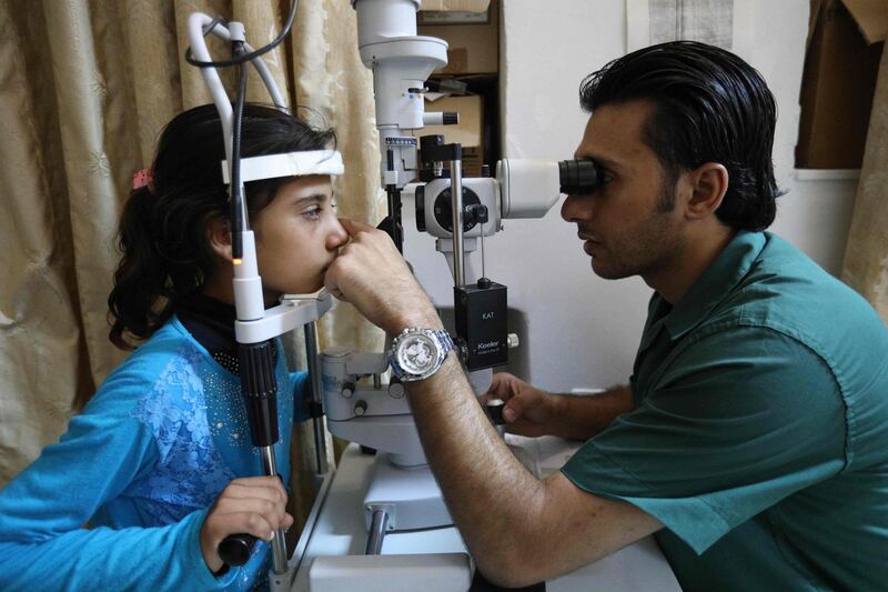 A Syrian girl eyesight is being tested by a doctor at a hospital in Idlib province, on September 4, 2018. - Aid agencies urged world powers to avoid "the greatest humanitarian catastrophe in Syria's seven-year war". Humanitarian workers "are already overwhelmed trying to provide shelter, food, water, schooling and healthcare," eight agencies said in a joint statement. (Photo by OMAR HAJ KADOUR / AFP)
