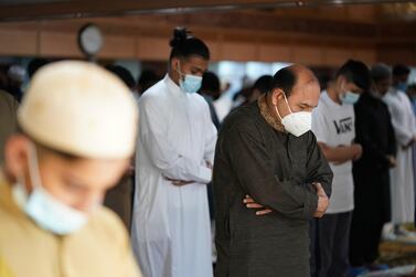 Men wearing face masks pray inside Manchester Central Mosque, after new rules on gatherings were announce. AP