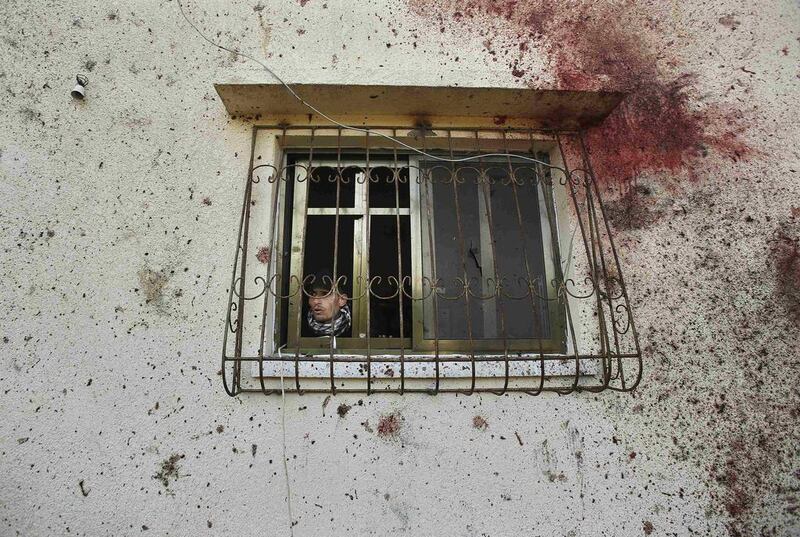 A Palestinian looks out a window framed in bloods tains after an Israeli air strike in Beit Hanoun, in the northern Gaza Strip on January 22, 2014. The strike killed two Gaza gunmen, one of whom Israel blamed for firing rockets across the border during former Israeli prime minister Ariel Sharon’s funeral last week. Suhaib Salem / Reuters