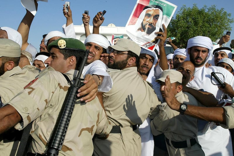 Emirati policemen control the crowd during the funeral of Sheikh Zayed bin Sultan al-Nahayan (seen in portrait) in Abu Dhabi 03 November 2004. Nahayan, the president and founding father of the United Arab Emirates, died 02 November 2004 after more than 30 years at the helm of his oil-rich country.      AFP PHOTO/RABIH MOGHRABI / AFP PHOTO / RABIH MOGHRABI