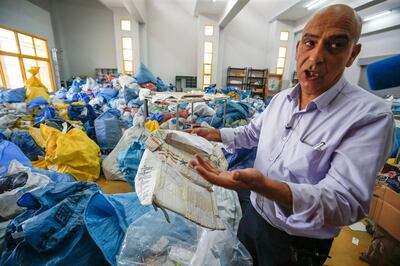 Ramadan Ghazawi, a Palestinian official at the central international exchange post office in the West Bank city of Jericho, holds up a damaged parcel, one of many items of previously undelivered mail dating as far back as 2010 which has been withheld by Israel, at the premises in Jericho on August 14, 2018. - Israel had held the post for years but handed it over to the Palestinian authorities after an agreement. (Photo by ABBAS MOMANI / AFP)