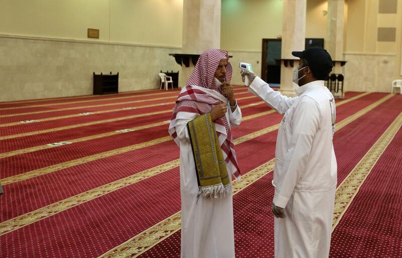A volunteer checks the temperature of a man as he arrives to perform the dawn prayer at a mosque in  Makkah. AFP