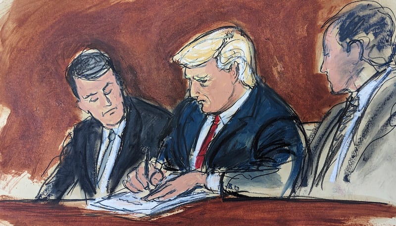 Mr Trump, flanked by his defence lawyers, signs his bond in federal court in a courtroom sketch. AP