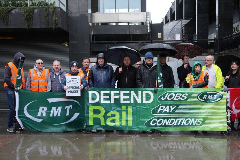 Mick Lynch, general secretary of the RMT, sixth left in blue jacket, joins union members on the picket line during a rail strike outside Euston station in London. AP