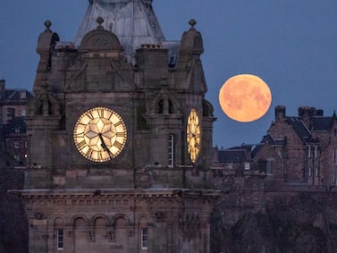 The pink moon sets behind the Balmoral Clock and Edinburgh Castle on Wednesday. PA