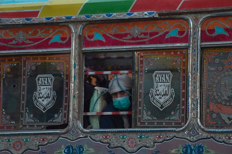 A man wearing a facemask as a preventive measure against the Covid-19 coronavirus, travels on a passenger bus in Karachi.  AFP