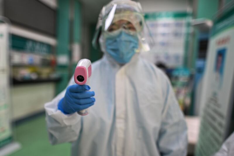 A medical worker prepares to check the temperature of an AFP photojournalist before a COVID-19 coronavirus test in Wuhan in China's central Hubei province. AFP