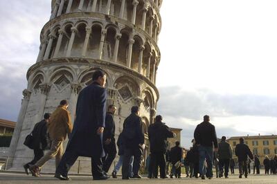 A group of Japqnese tourists gets ready to visit the leaning tower of Pisa 15 December 2001, the day of the official opening to the public after an 11-year closure for restoration after engineers judged the tower too fragile and unstable. For most of the past decade, the 54.5-meter tall marble monument was girdled in steel and anchored by a pair of slender steel "suspenders'' running across the surrounding square. By using hundreds of tons of counterweights at the base and extracting soil from under the foundation, engineers guided the tower back to where it was in 1838. 
AFP PHOTO ALBERTO PIZZOLI (Photo by ALBERTO PIZZOLI / AFP)
