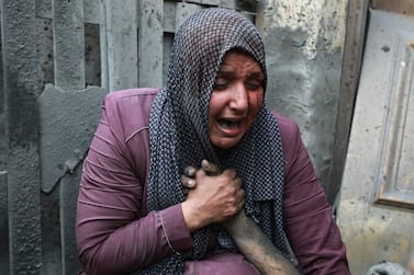 A wounded Palestinian woman cries as she holds the hand of her dead relative outside her home following Israeli airstrikes that targeted their neighbourhood in Gaza City, Monday, Oct.  23, 2023.  (AP Photo / Abed Khaled)