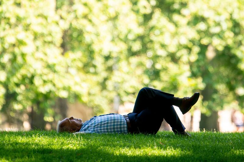A man reclines in the shade during a spell of hot weather in Green Park, central London. The amber alert is the first issued by the Met Office since the UK's national weather service launched its extreme heat alert system at the start of June.