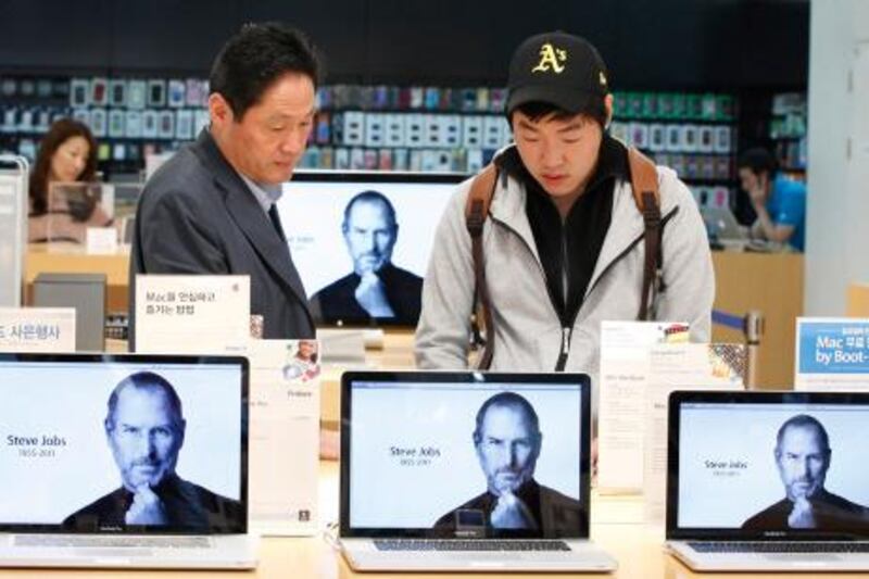 Customers look at products behind computer monitors displaying the obituary of former Apple CEO Steve Jobs at an Apple Store in Seoul October 6, 2011. Apple Inc co-founder and former CEO Steve Jobs died on Wednesday at the age of 56, after a years-long and highly public battle with cancer and other health issues.   REUTERS/Jo Yong-Hak  (SOUTH KOREA - Tags: BUSINESS OBITUARY SCIENCE TECHNOLOGY TPX IMAGES OF THE DAY) *** Local Caption ***  SEO101_APPLE-JOBS_1006_11.JPG