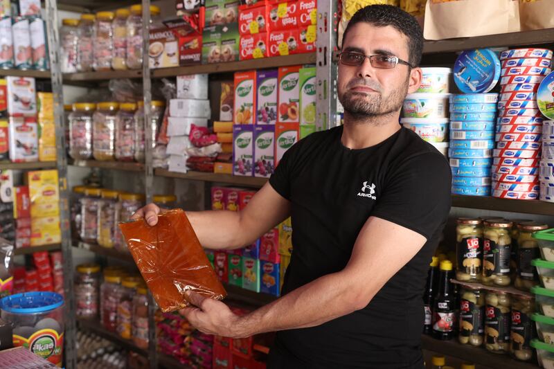A Syrian shopkeeper shows a pack of dried apricot paste which can be dissolved to make Qamar Al Din, in Binnish in Idlib.