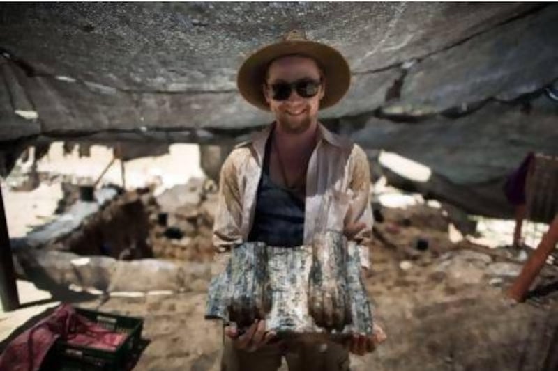 Excavation volunteer Joshua Talbot displays the remains of a sphinx with a hieroglyphic inscription between its paws, found during excavation works in the archeological site of the ancient Tel Hazor.