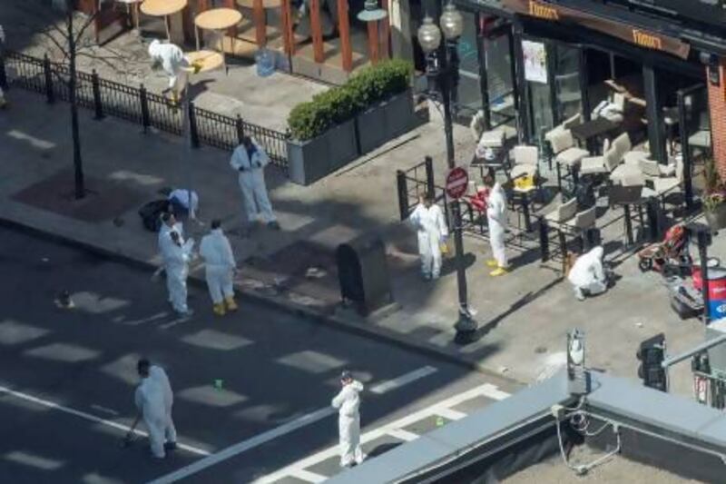 Evidence technicians work at the site of one of the bombings on Boylston Street as an investigation continues into the bombings near the finish line of the Boston Marathon.