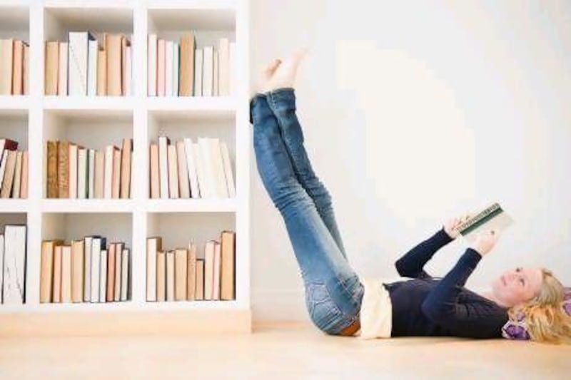Young woman reading next to bookshelf