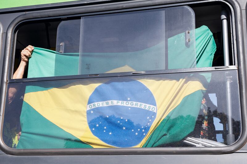 A Bolsonaro supporter waves Brazil's flag from a police bus in Brasilia. Reuters