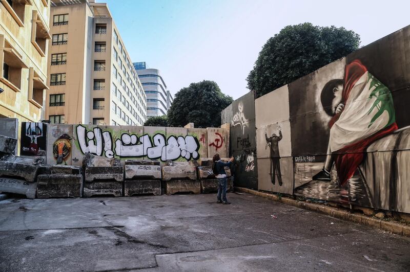 A woman takes pictures of graffiti art made by anti-government protesters on a barrier erected to save the great theater at the entrances leading to Riad Al-Solh square in Beirut, Lebanon.  EPA