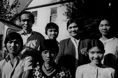 Members of the Nguyen Van Toan family, which arrived in Denver in 1975, pose behind a photo taken of the same group 10 years earlier. Getty Images