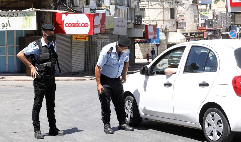 Palestinian policemen stop a car in an empty street, in the West Bank city of Nablus. Palestinian authorities have announced a five-day lockdown to curb the spread of Coronavirus in the West Bank. EPA