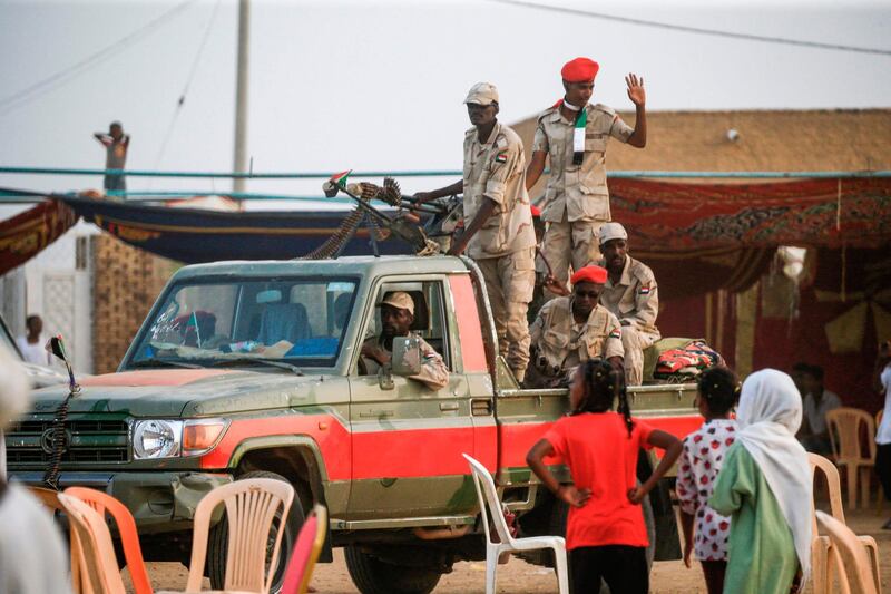 Members of Sudan's Rapid Support Forces (RSF) paramilitaries speak to girls from atop a technical (pickup truck mounted with a machine gun turret) during a rally in the village of Qarri, about 90 kilometres north of Khartoum.  AFP