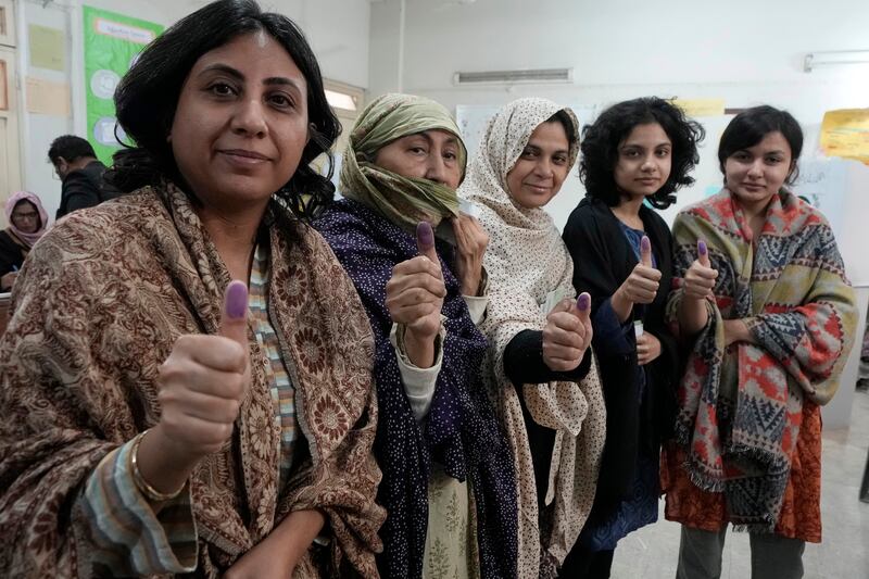 Women show their ink-stained thumbs after voting in Karachi. AP