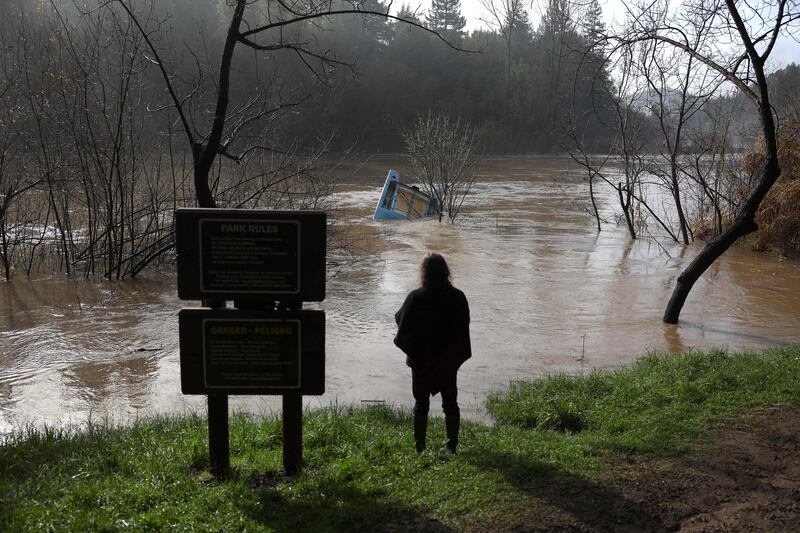 A resident looks at a boat caught in a tree in the Russian River in Rio Nido, California. Getty / AFP