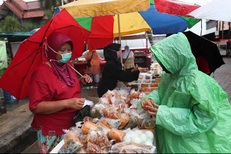 A street vendor wears her face mask to help stop the spread of the coronavirus as she sells food for iftar, the breaking of the Ramadan fast, in Tangerang, Indonesia. The world's Muslims have begun Ramadan with dawn-to-dusk fasting amid restrictions imposed to slow the pandemic that left many confined to their homes and public venues like parks, malls and even mosques are shuttered. AP